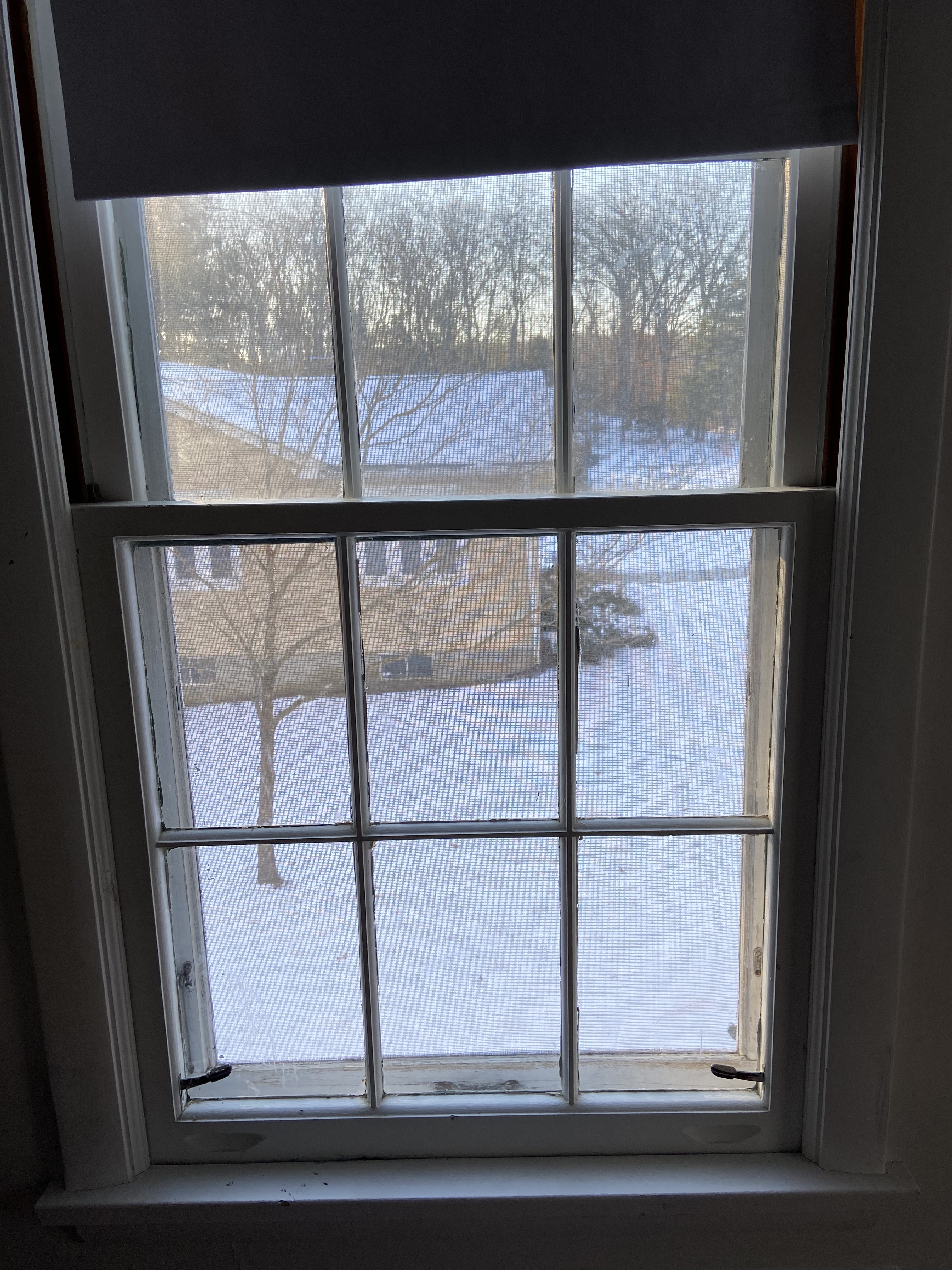 This is a view outside to a snowy landscape. Outside the window is the side of a yellow house